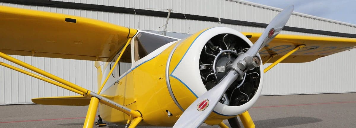 Close up of a yellow and white Stinson Reliant's engine and propeller.