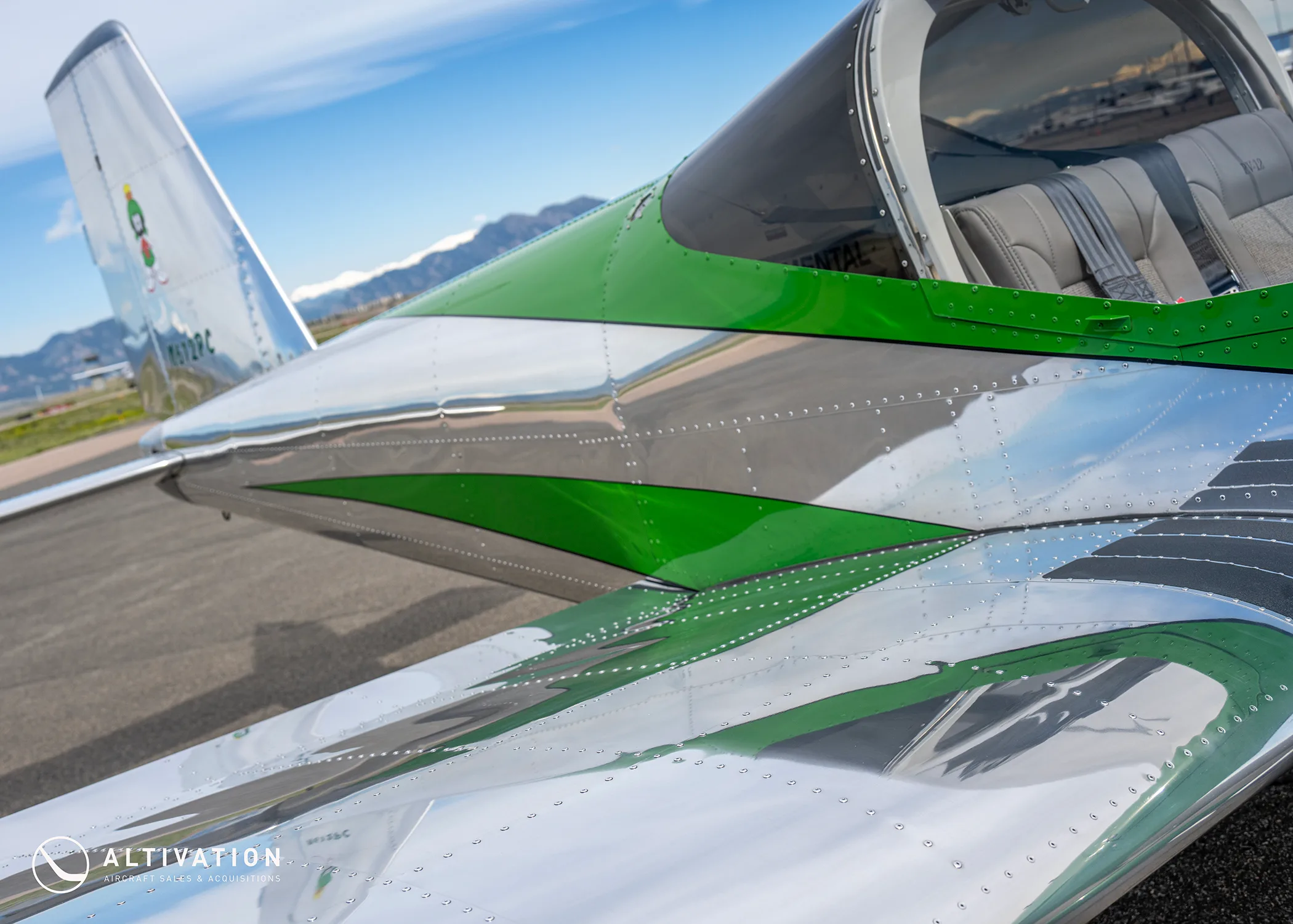 A close-up view of the green and polished aluminum fuselage and wing of a Vans RV-12 aircraft.
