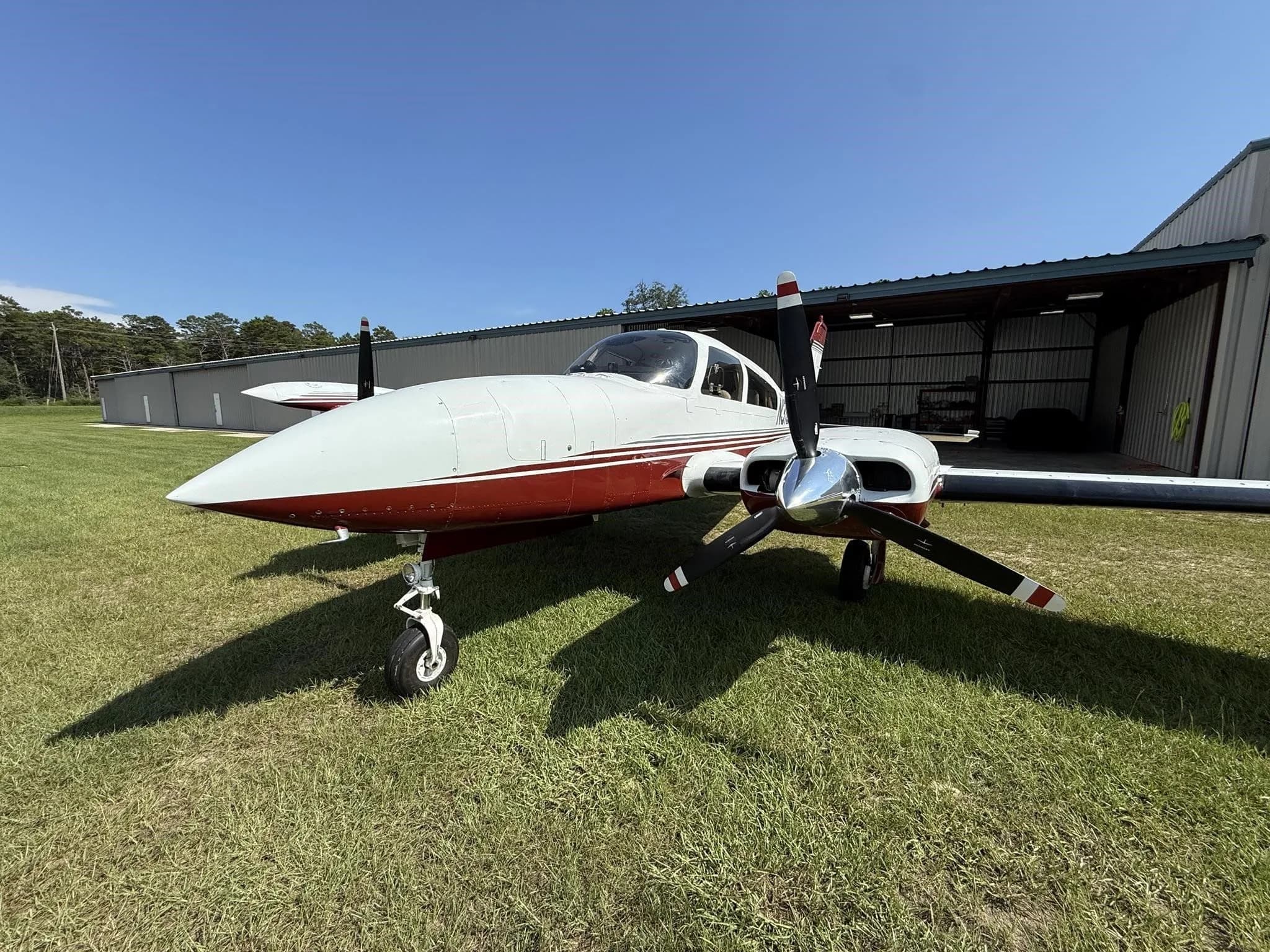 Front-right low angle view of a white and red twin-engine aircraft (N310Z) parked on grass.