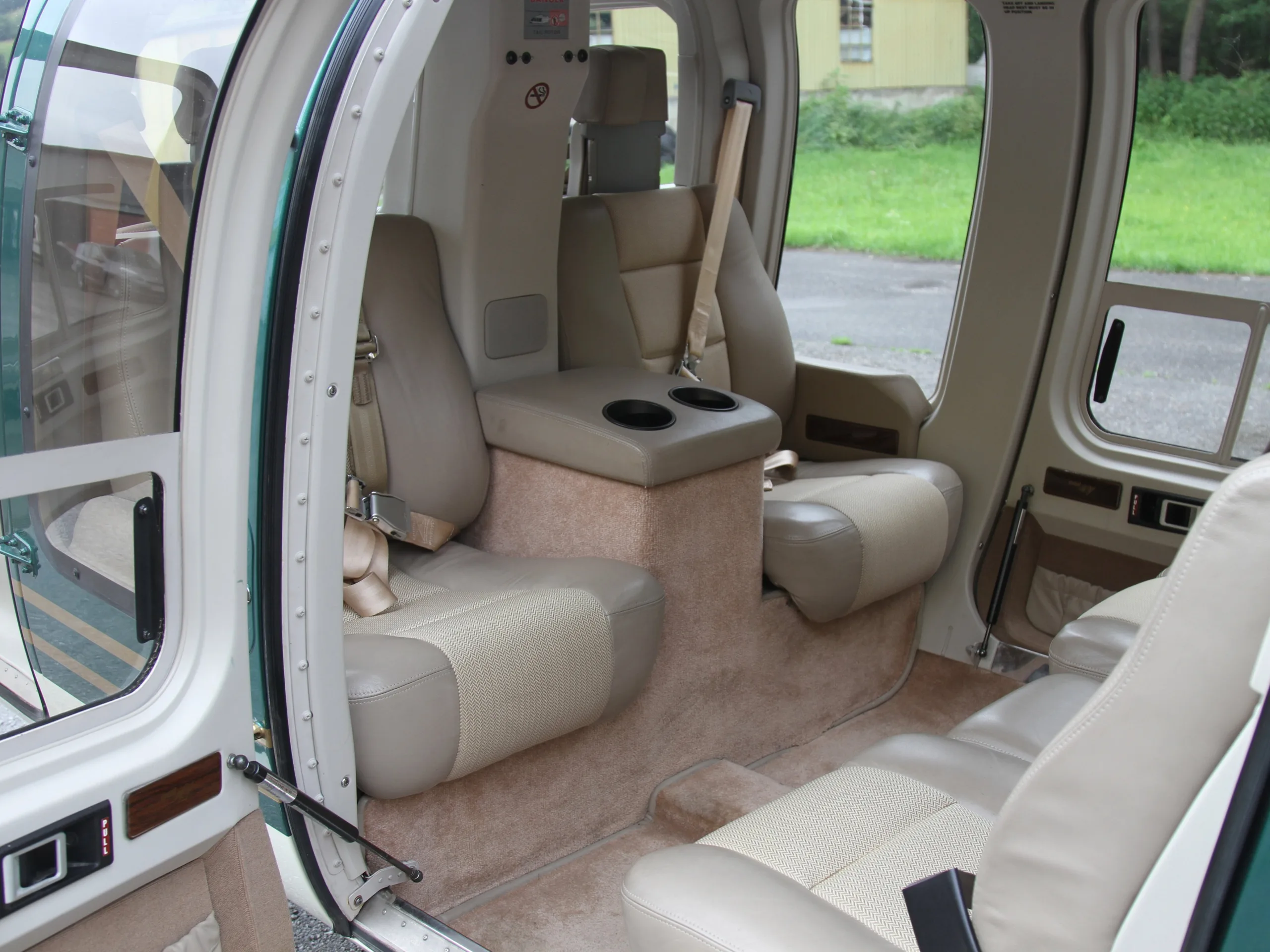 The helicopter's interior features tan leather seats and a center console with cupholders.