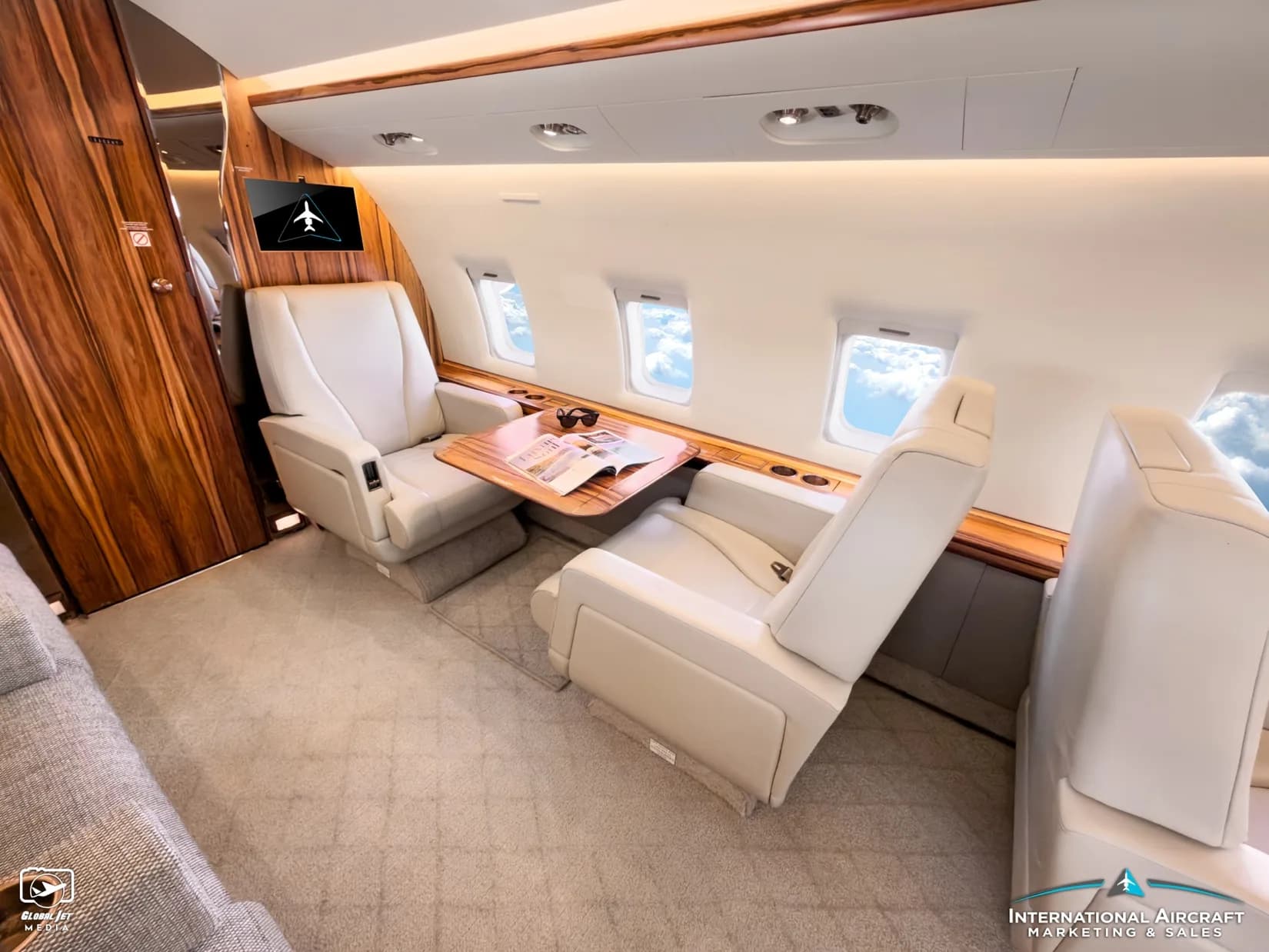 Cabin of the Bombardier Challenger with white leather seats and wood tables.