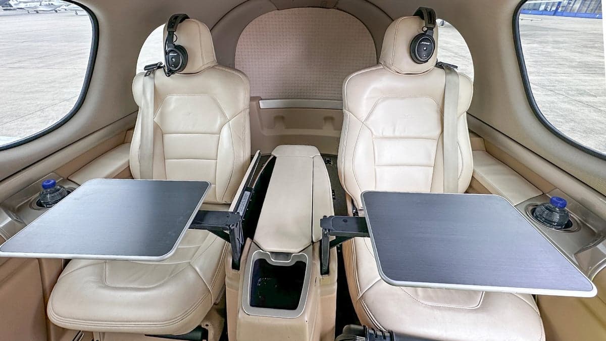 The interior of the Cirrus Vision Jet features cream-colored leather seats with fold-down tables.