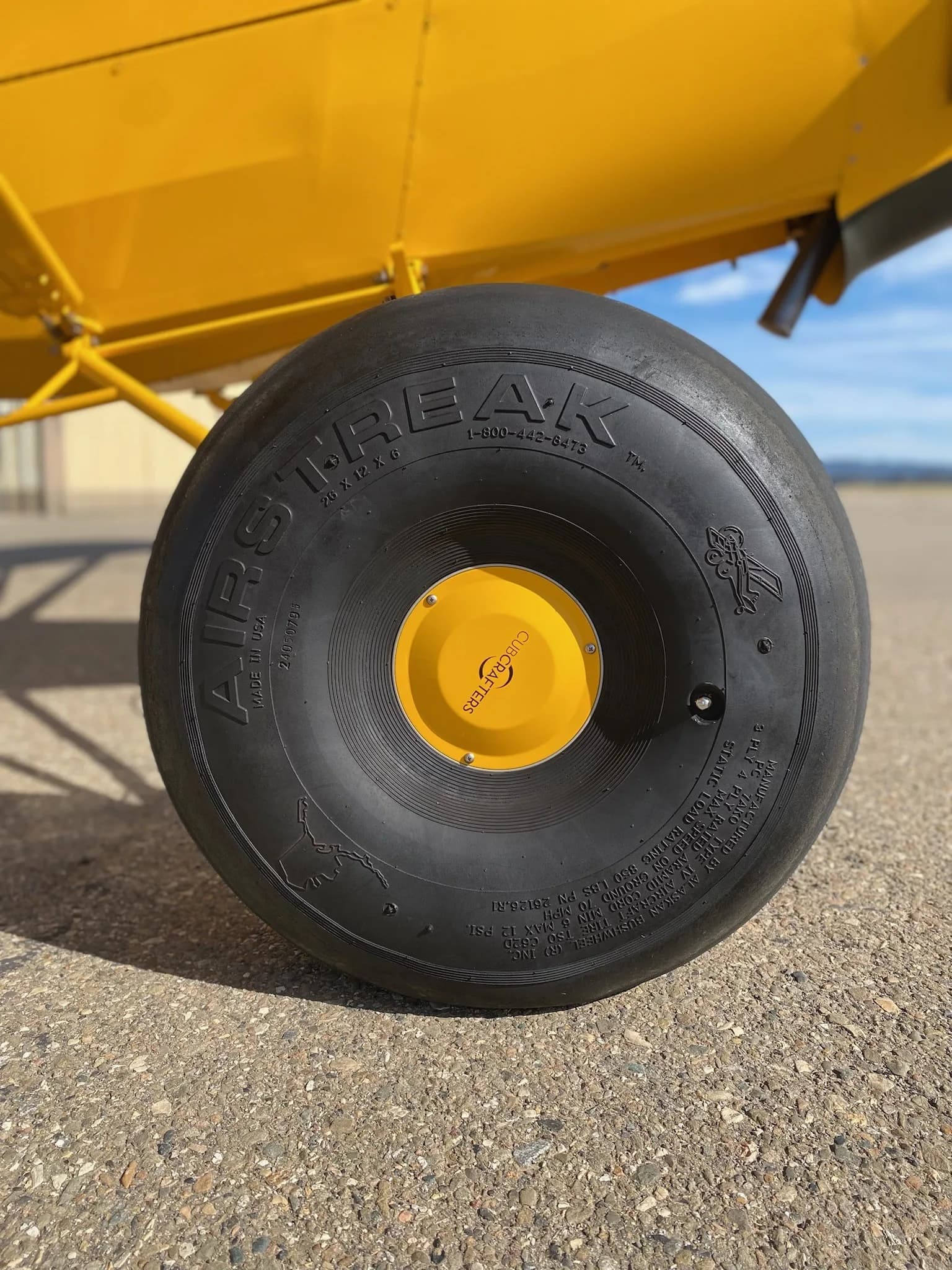 Close-up of the large tire on a yellow Carbon Cub aircraft.