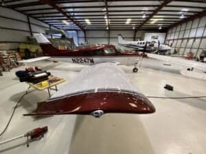 N2247M is shown in a hangar with a red and white paint scheme, with a wing in the foreground.