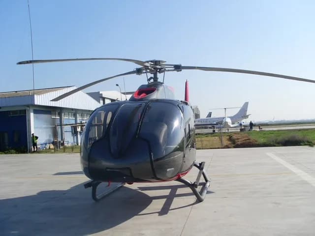 Front view of a gray and red helicopter on the tarmac.