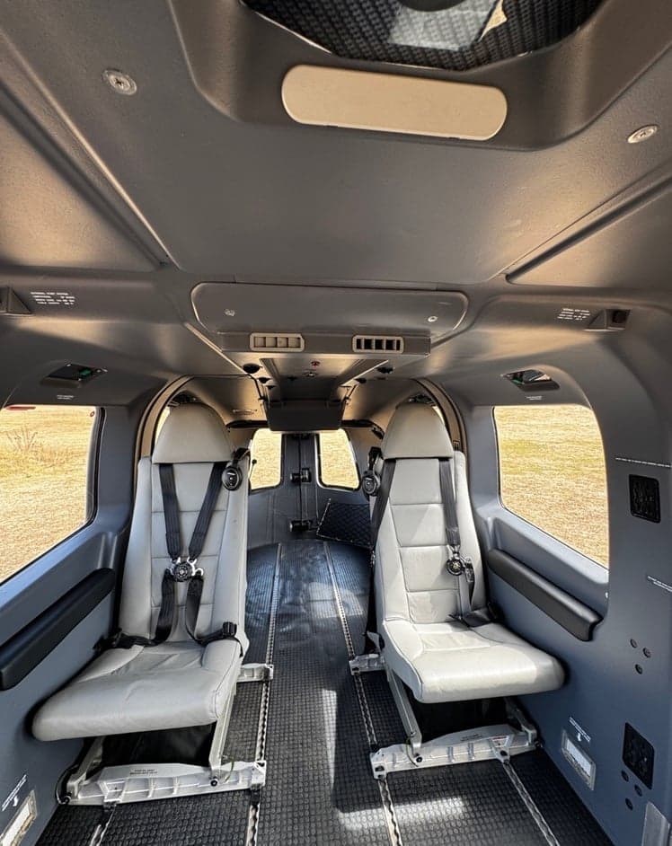 Helicopter cabin with two gray seats and seatbelts.