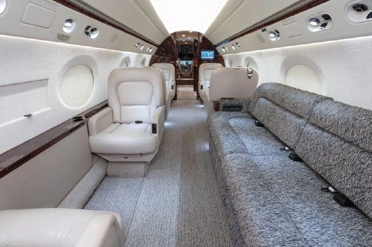 Interior view of the aircraft with cream-colored leather seats and a couch.