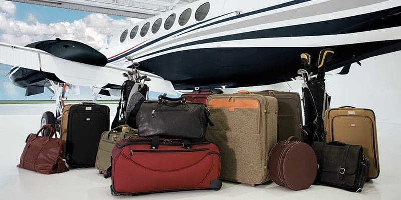 Various pieces of luggage and golf bags are displayed next to a King Air 350i in a hangar.