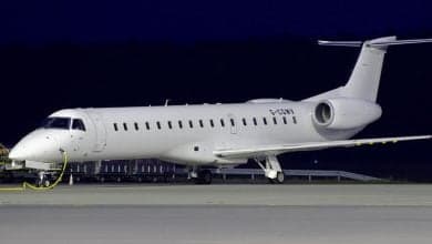 Side view of a white Embraer Legacy 600 aircraft on the tarmac at night.