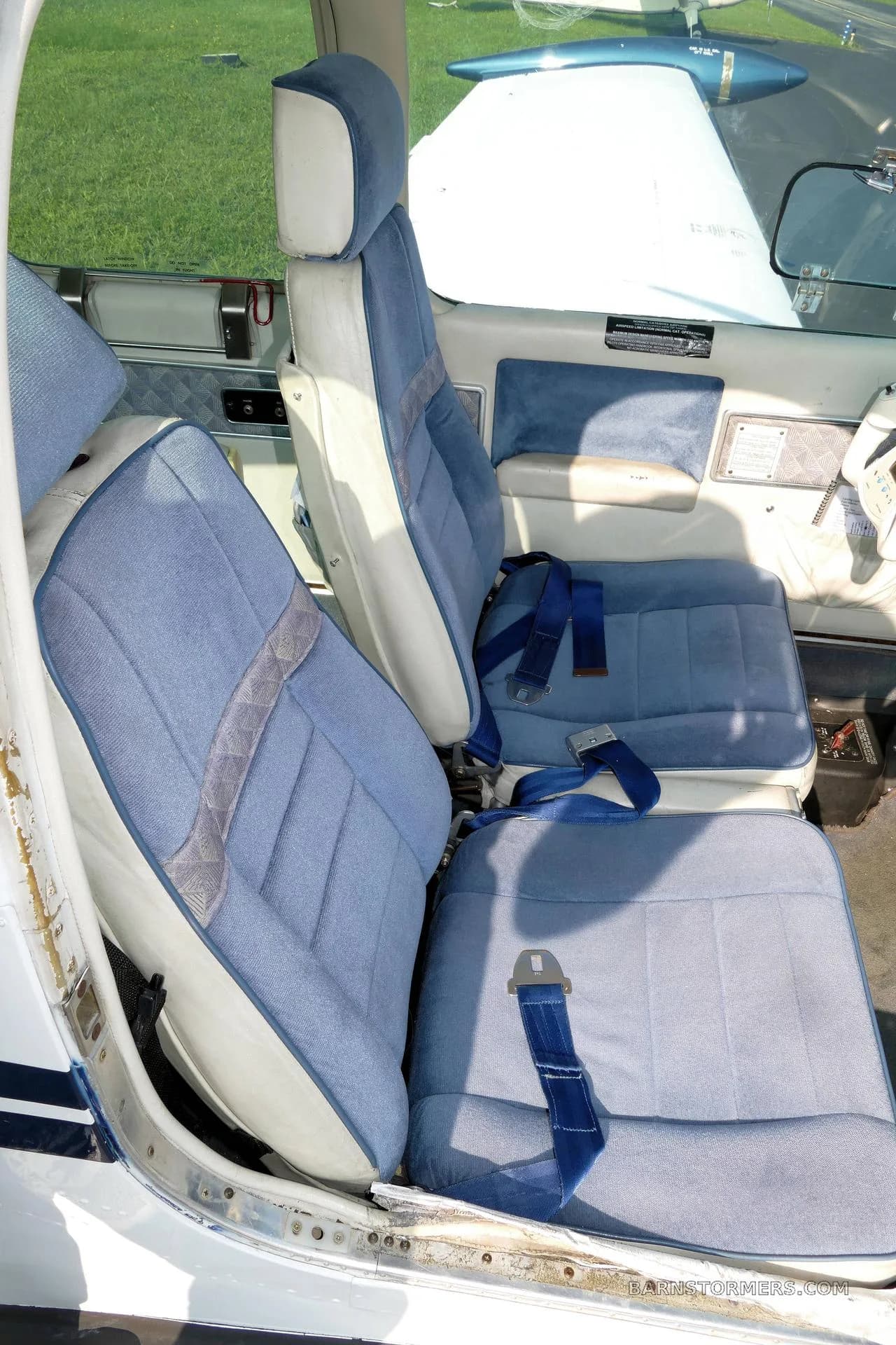 The light blue fabric and white leather interior seats of a small aircraft cabin.