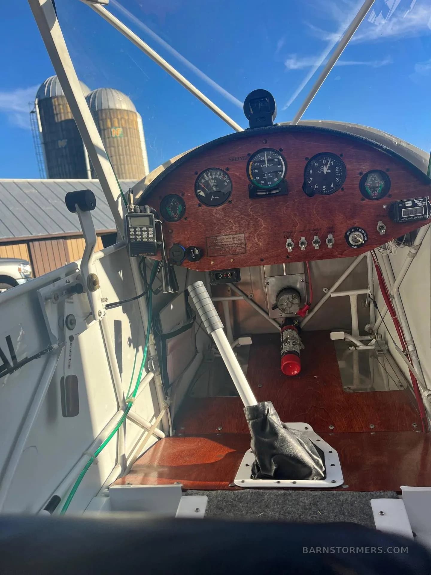 The cockpit of an experimental aircraft with a wooden instrument panel, various gauges, and a control stick.