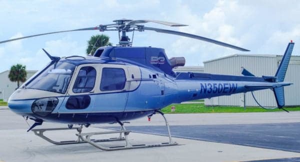 A blue Eurocopter AS350B3 Ecureuil helicopter is parked on the tarmac.