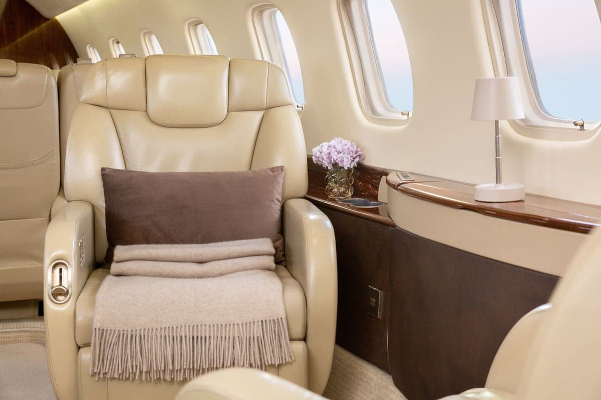 Close up of a leather seat with a pillow and blanket in the Embraer Legacy 500 cabin.