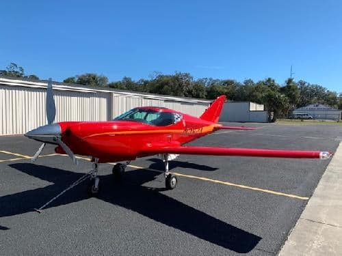 A red aircraft with registration N54JX parked on the tarmac.