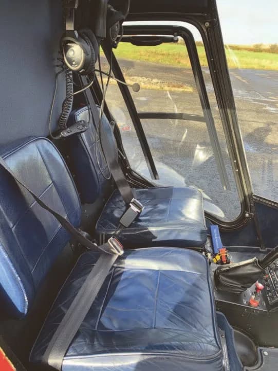 The blue leather seats and part of the cockpit controls inside a helicopter.