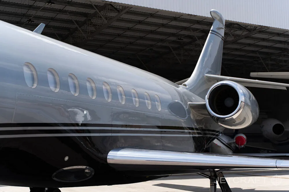 A close-up view of the rear fuselage, engine, and tail of a silver and black business jet.