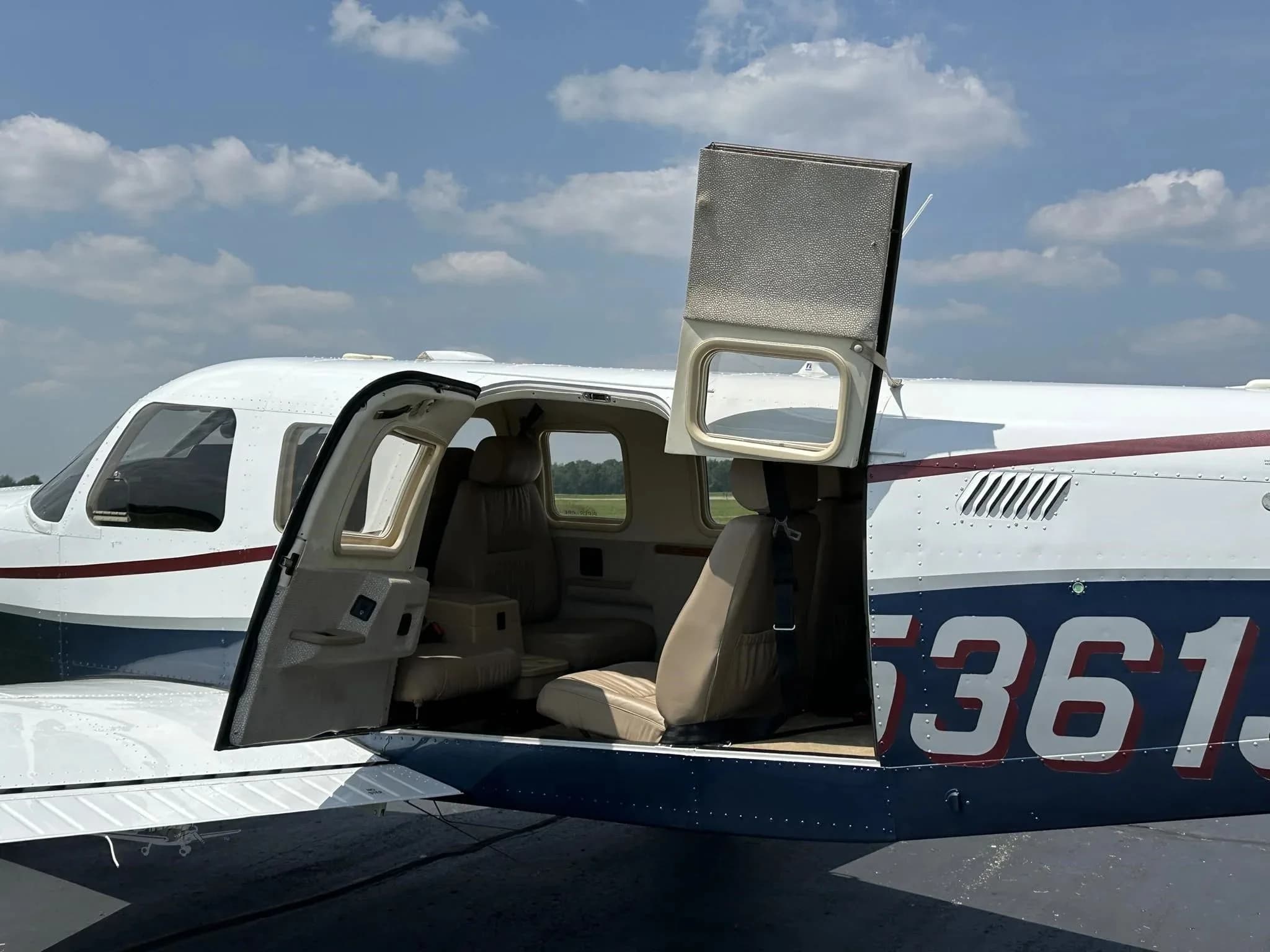 The open cabin door of the Piper Saratoga II TC reveals tan leather seats inside.