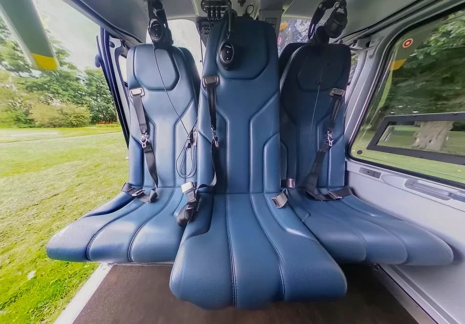 Interior view of the helicopter cabin with three blue leather seats.