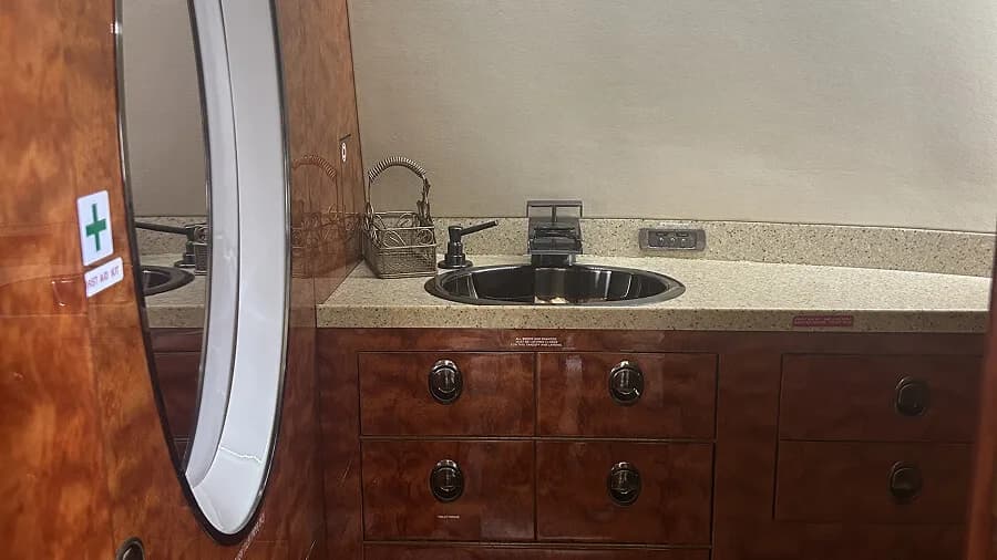 The aircraft lavatory or galley area with a sink, counter, and polished wood cabinetry.