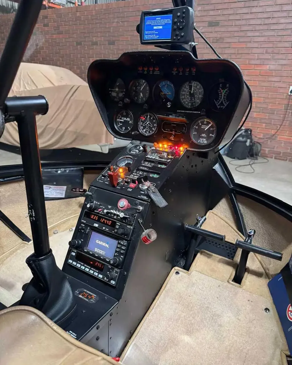 The instrument panel and central console of a helicopter cockpit are shown, with a GPS unit mounted on top.