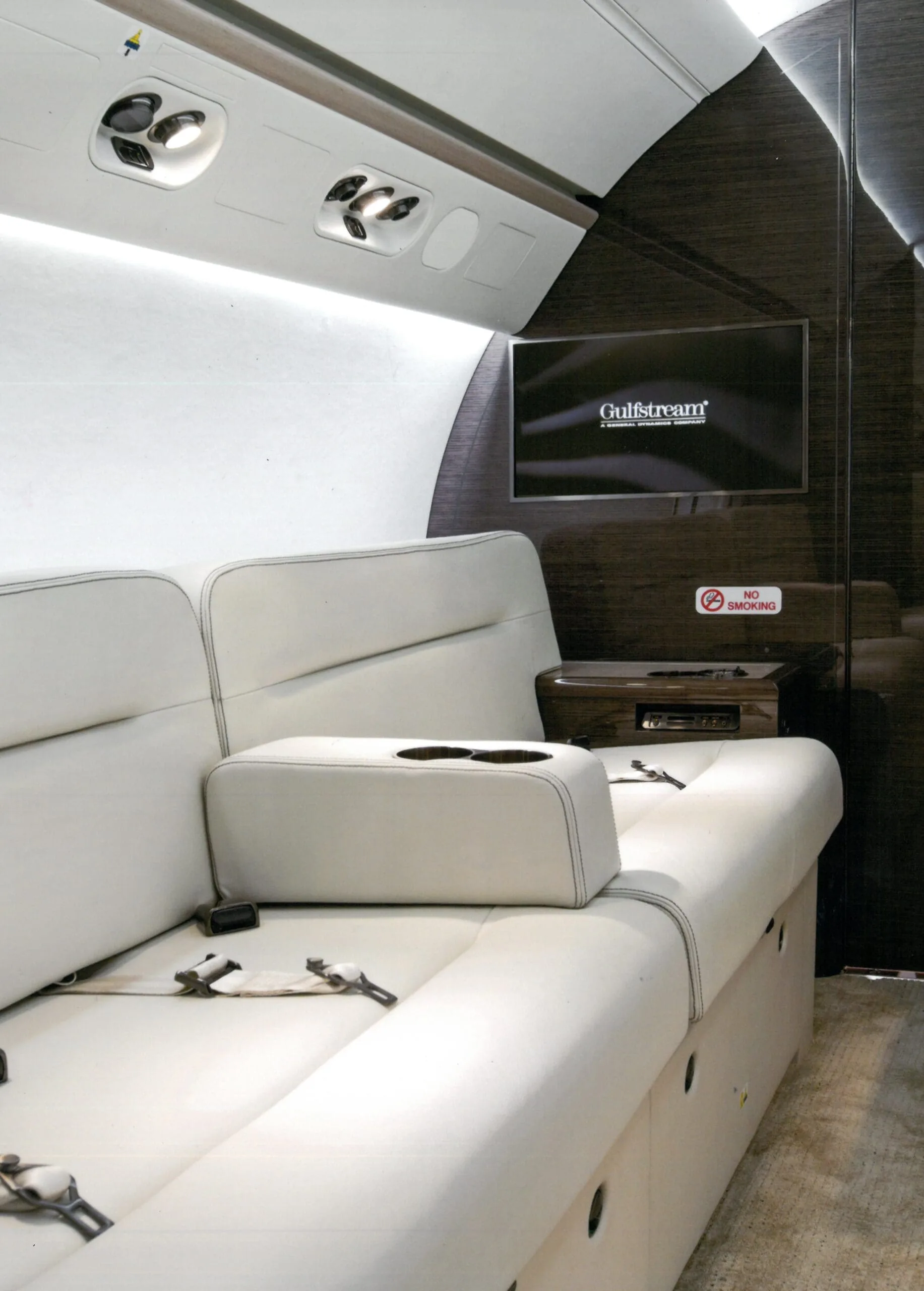 View of the aircraft cabin with white leather seats and a Gulfstream TV screen.