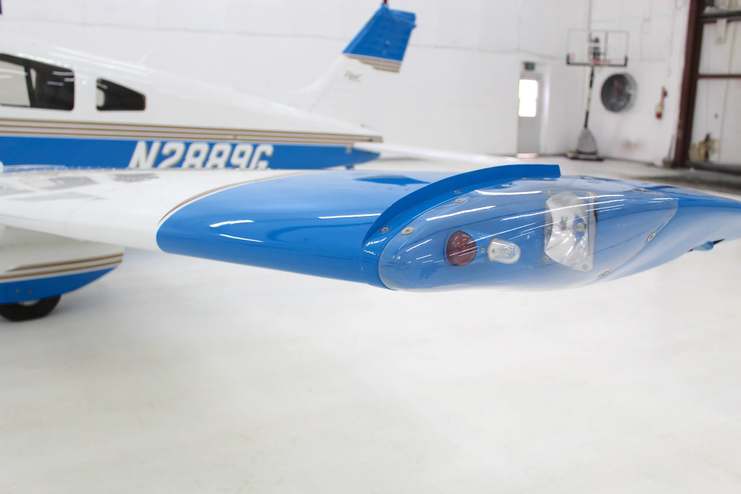 A close-up view of the right wingtip and tail section of the white and blue Piper Dakota aircraft.