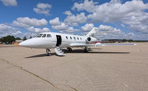 A Hawker jet with registration N998BM parked on the tarmac with the stairs down.