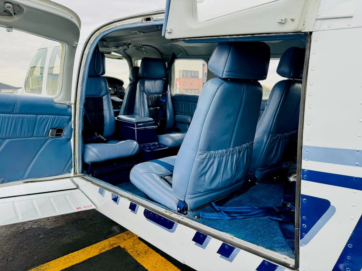 View of the aircraft cabin showing blue leather seats and blue carpet with the door open.