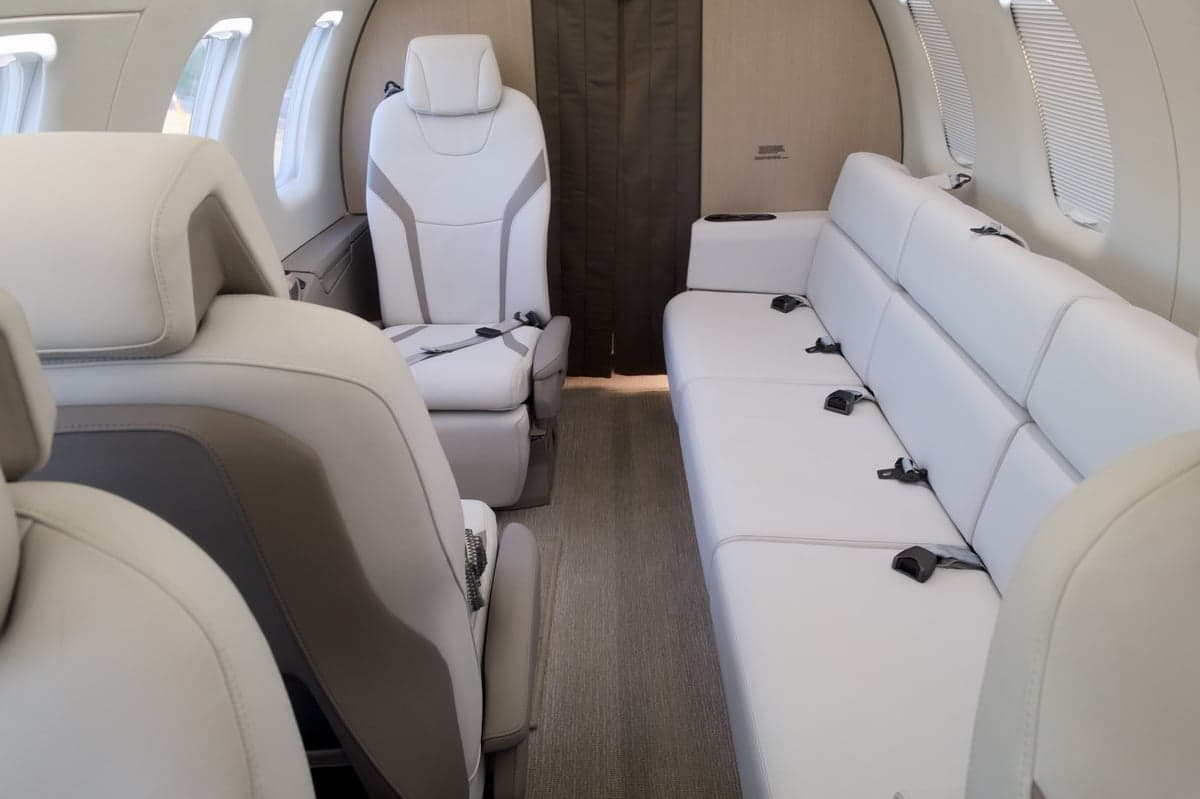 View of the aircraft's interior cabin with white leather seats and a couch.