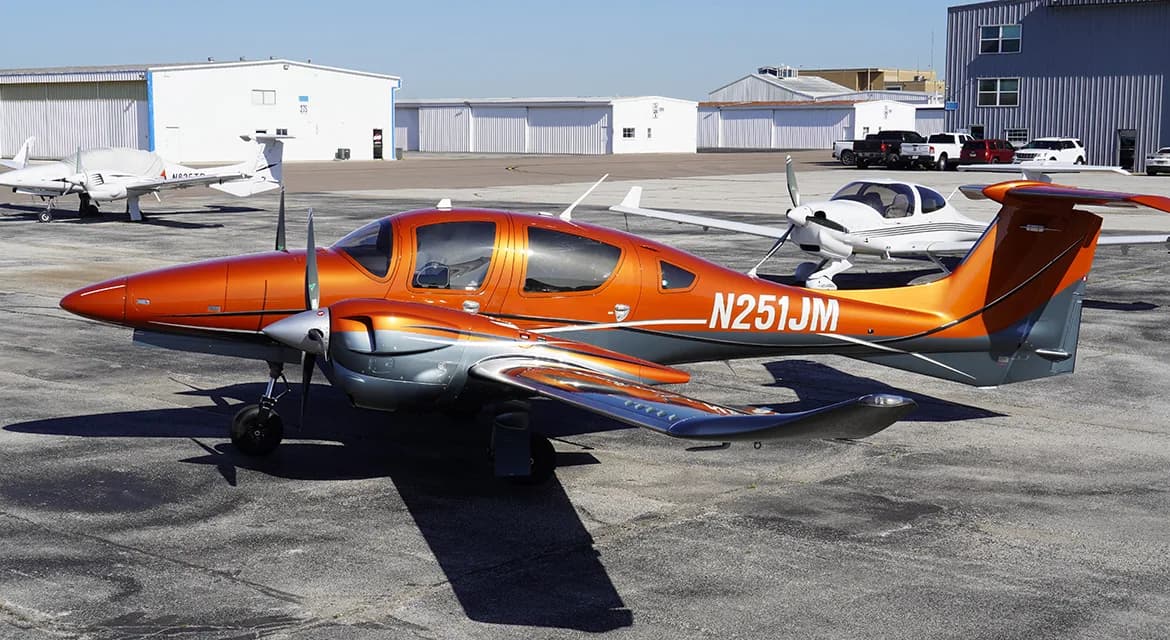 Diamond DA62 aircraft with orange and gray paint scheme parked on the tarmac.