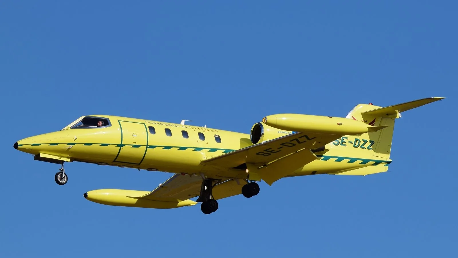 Yellow Scandinavian Air Ambulance jet in flight.