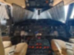 A blurry view of the Challenger aircraft cabin with beige leather seats.