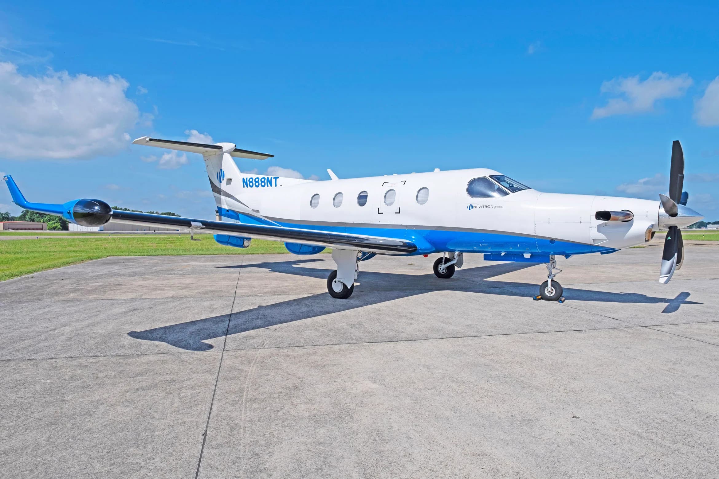 A white and blue Pilatus PC-12 aircraft, tail number N888NT, parked on a tarmac with its propeller and tail visible.
