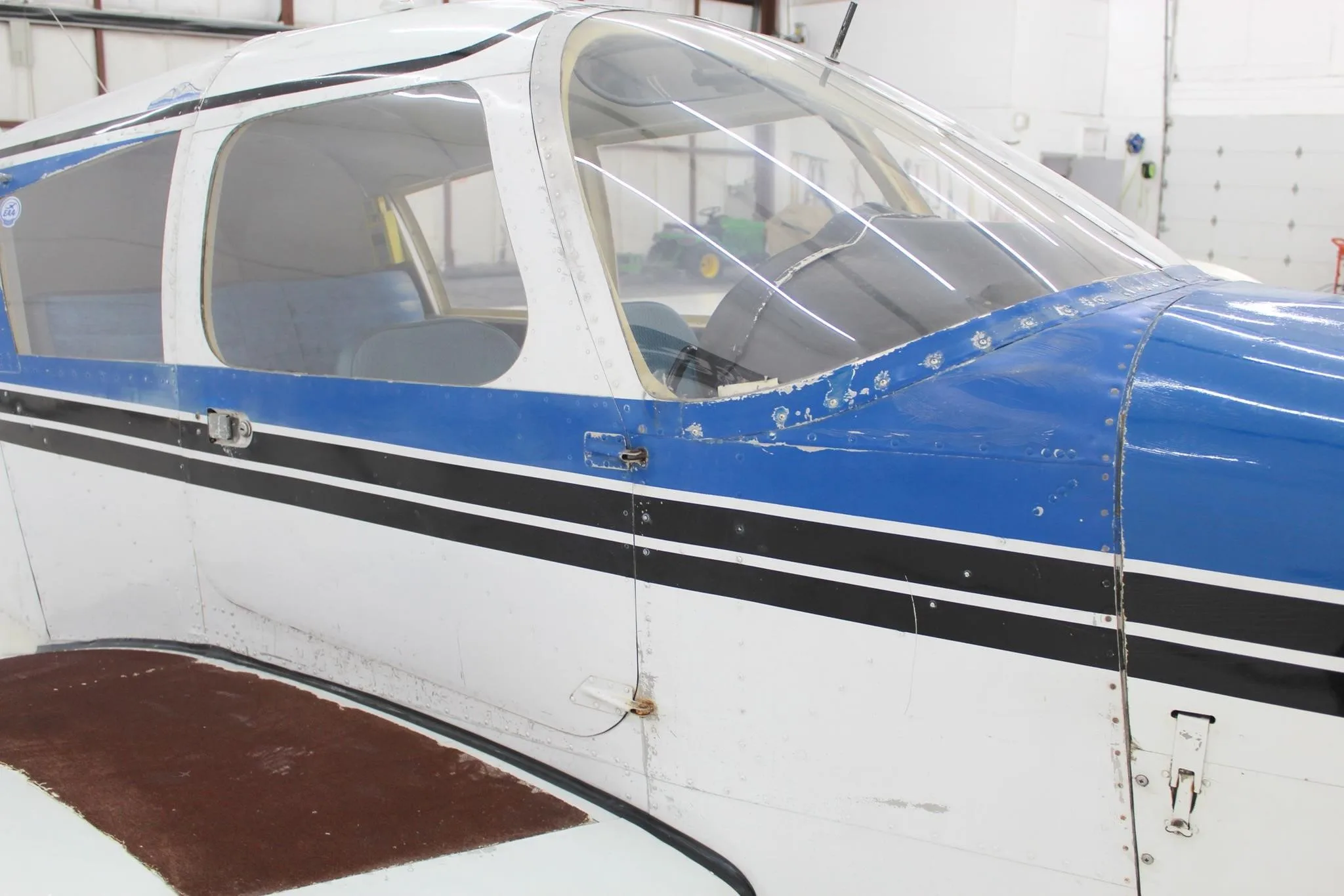 Side view of the cockpit and passenger door of a blue and white single-engine aircraft.