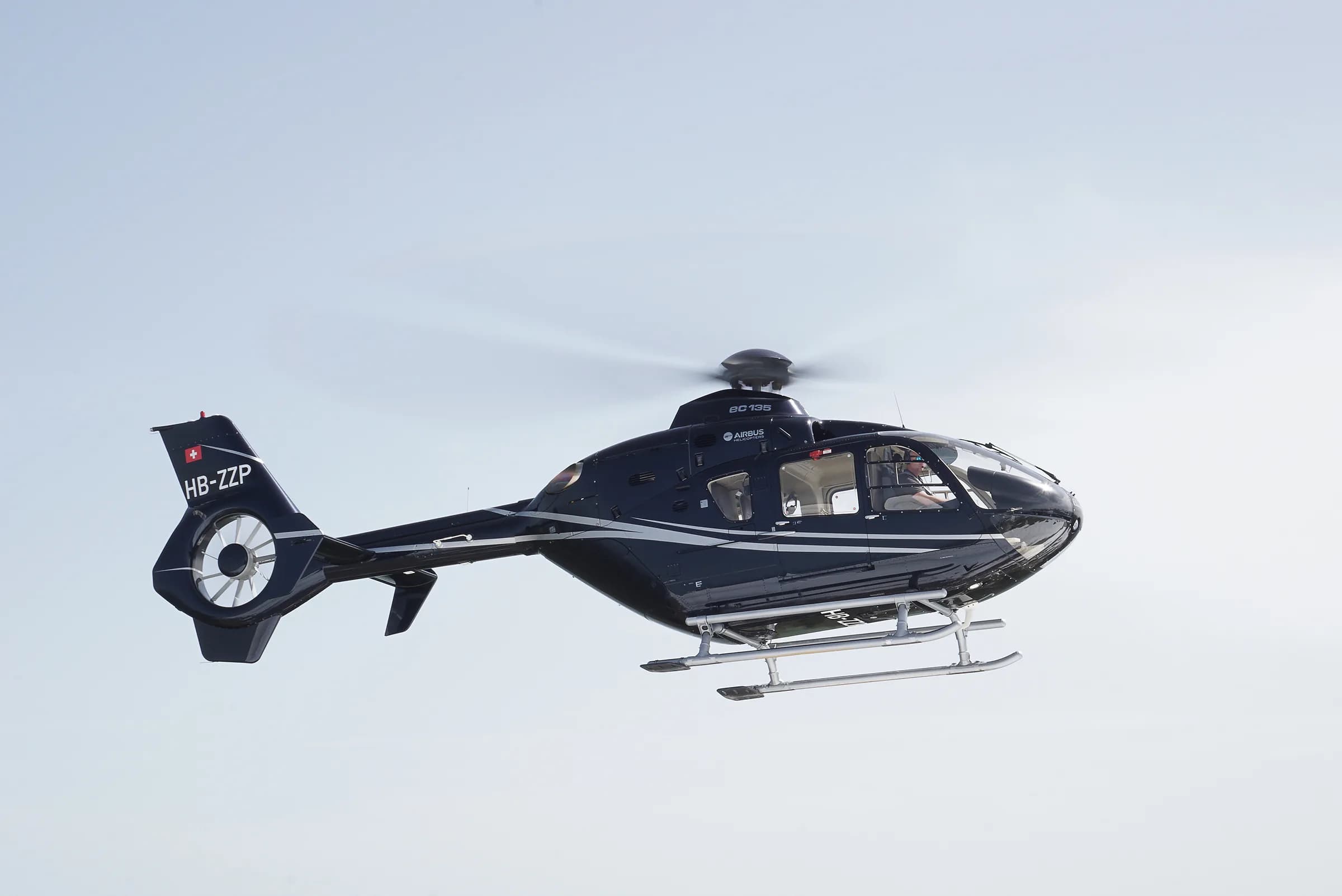 An Airbus EC135 helicopter in flight with a dark blue and white paint scheme.