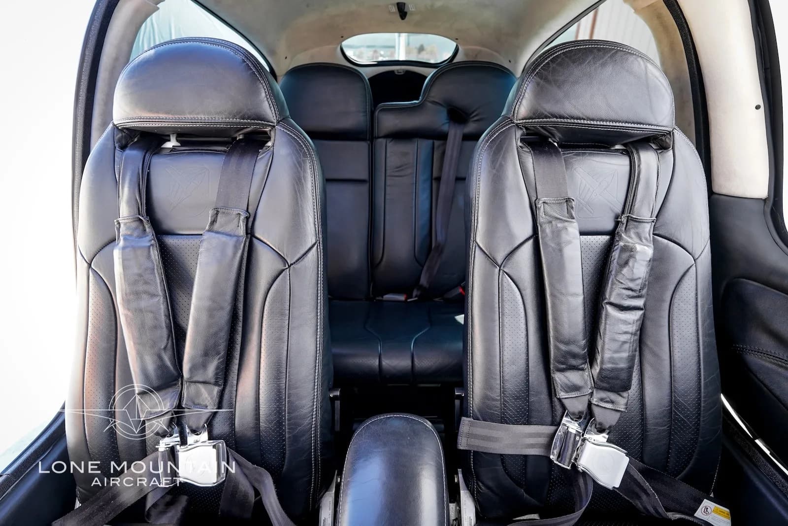 The black leather front seats of the Cirrus SR22 aircraft cabin, showing seatbelts and headrests.