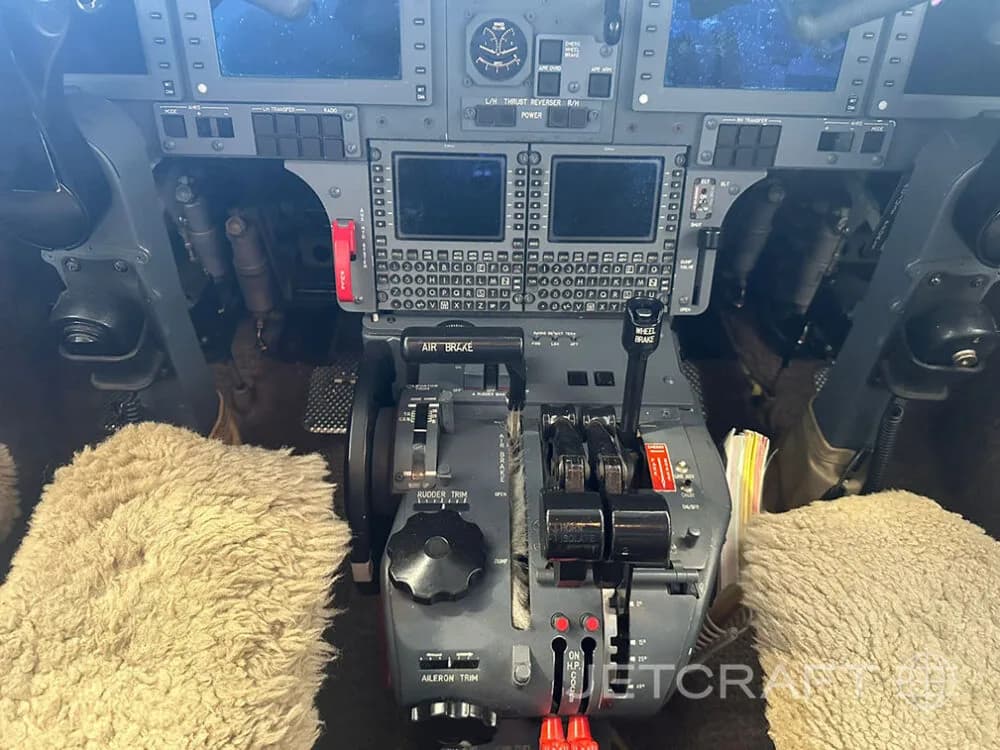 The cockpit of a jet aircraft, showing the throttle quadrant, instrument panel, and displays.