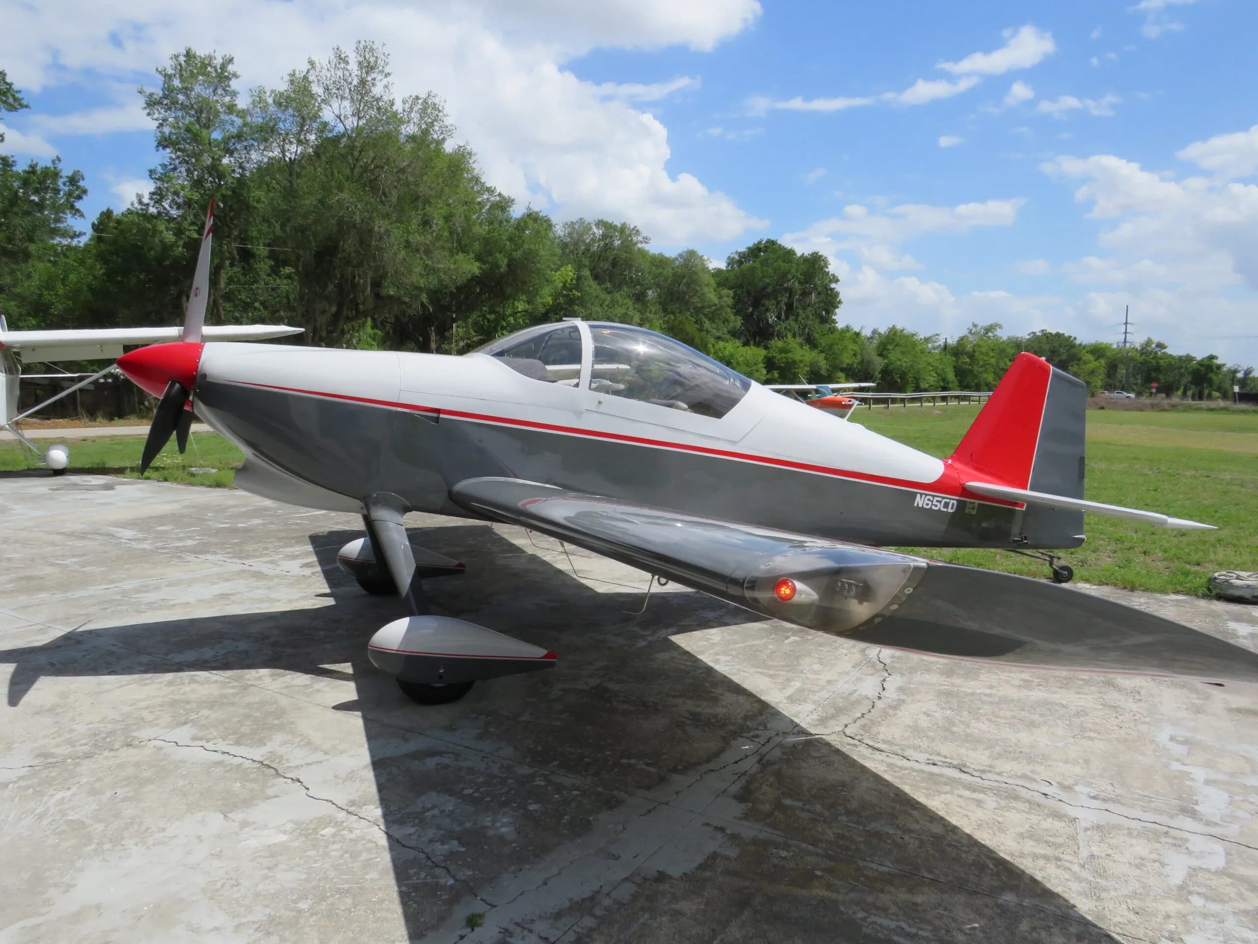 Full side view of a white and grey aircraft with a red tail and red stripes, registration N65CD visible.