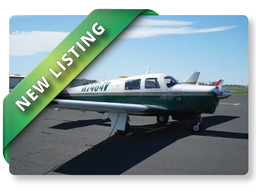 A green and white single-engine aircraft, N7404V, parked on an asphalt apron on a sunny day.