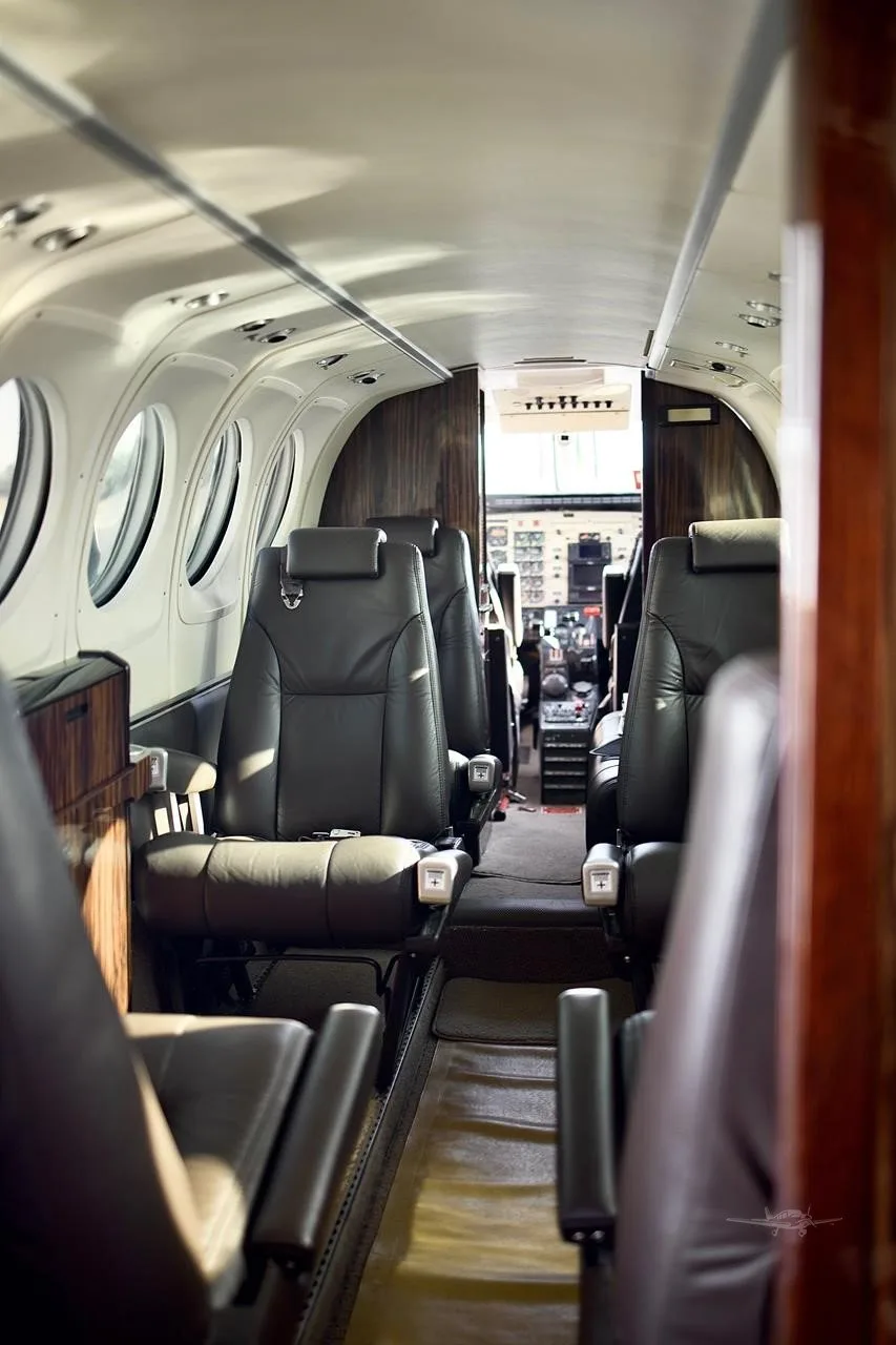 The aircraft's cabin interior with dark leather seats arranged in a club configuration, looking towards the cockpit.