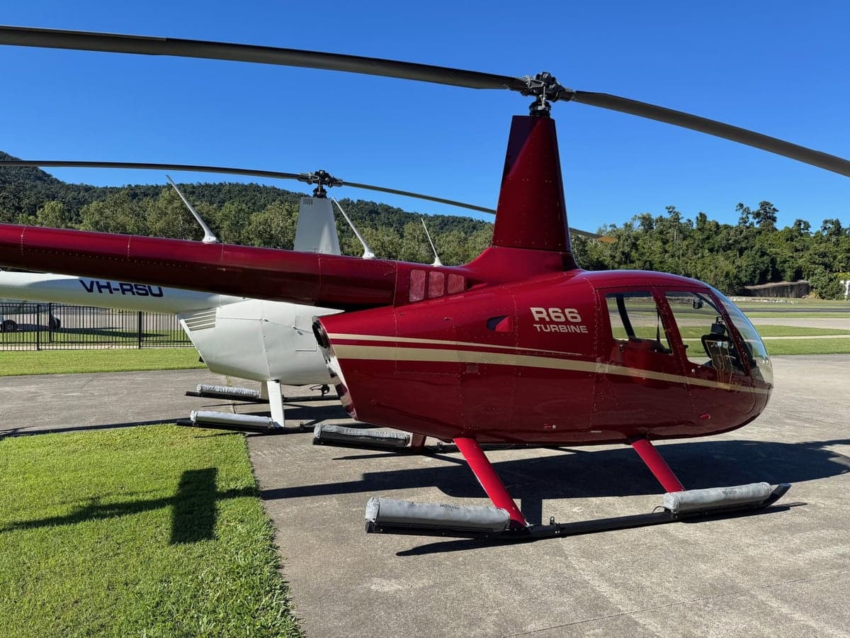 A red R66 Turbine helicopter parked on a tarmac.