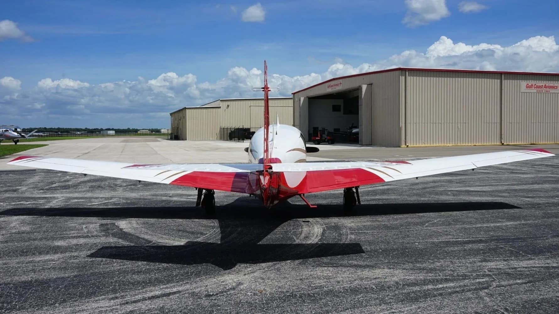 A rear view of the red and white aircraft, N33YZ, showcasing its tail and wings on an airfield.