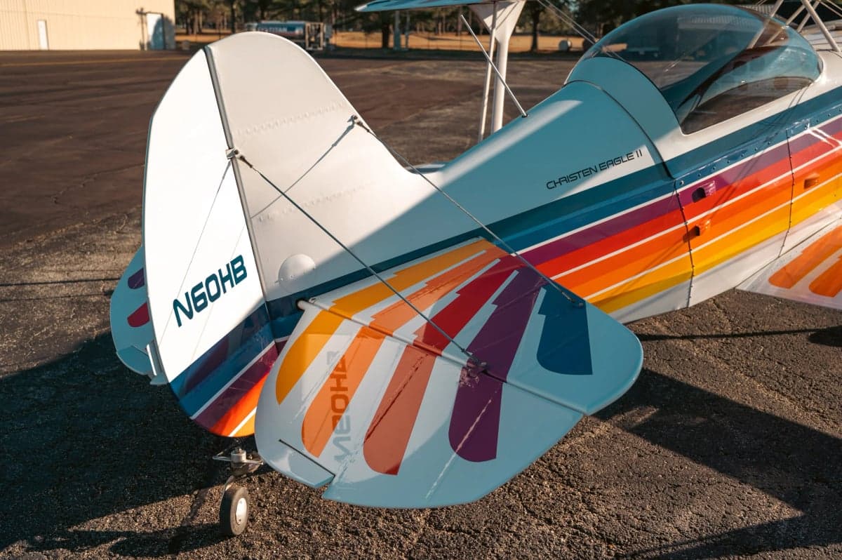 Rear view of the Christen Eagle II biplane with a colorful paint scheme showing the tail number N60HB.