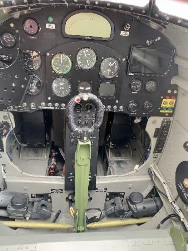 The cockpit of a P-40 Warhawk replica aircraft showing the instrument panel and controls.