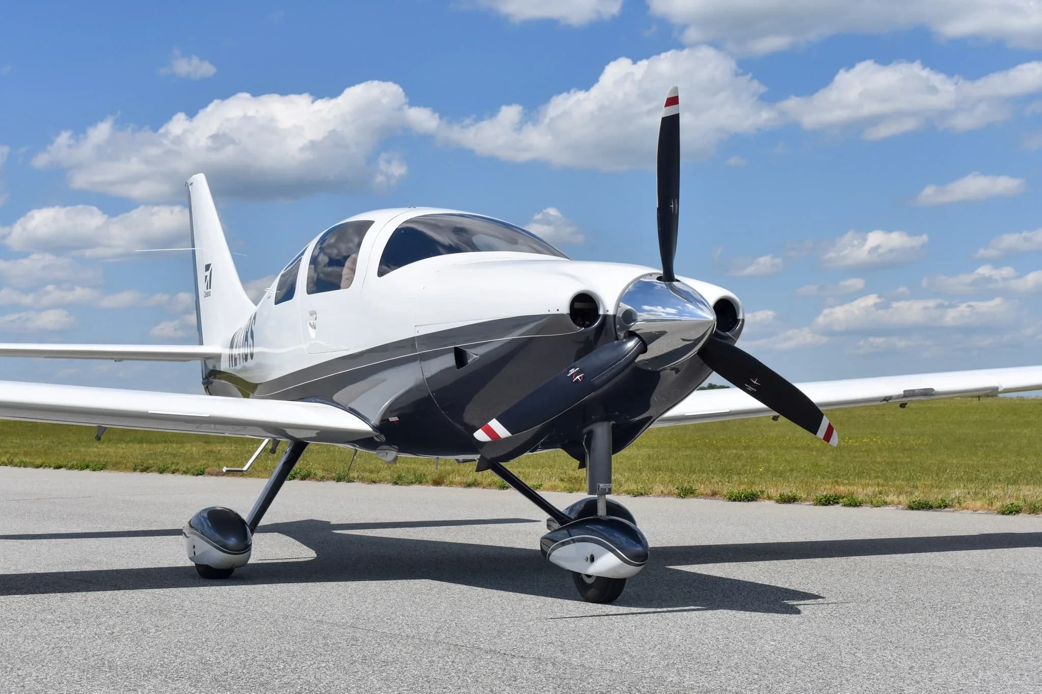 A front-quarter view of a white and dark grey Cessna TTx (Corvalis 400) aircraft, N241BS, parked on an airfield.