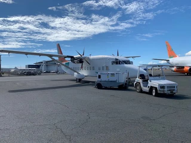 A Transair aircraft is parked on the tarmac at an airport.