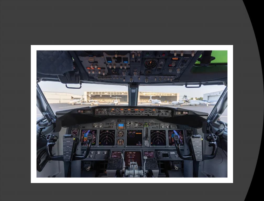 The modern cockpit of a Boeing 737, showing the instrument panel, yokes, and overhead panel.