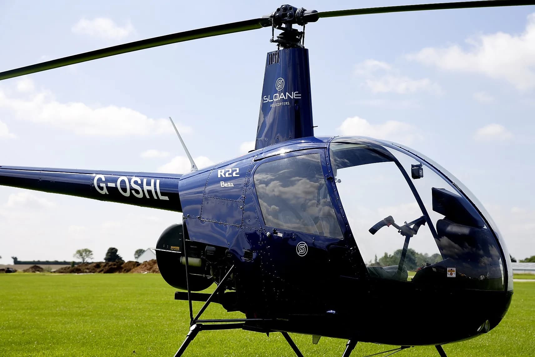 Close-up of a blue Robinson R22 helicopter on the ground.