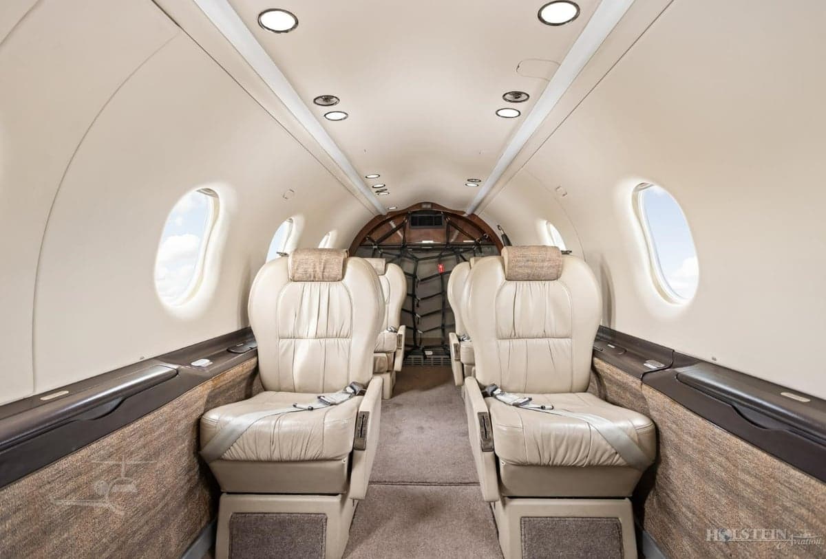 Full view of the Pilatus PC-12 cabin with leather seats and cargo netting.