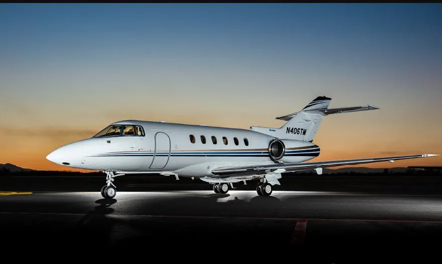 A Citation jet with tail number N406TM is parked on the tarmac at sunset.